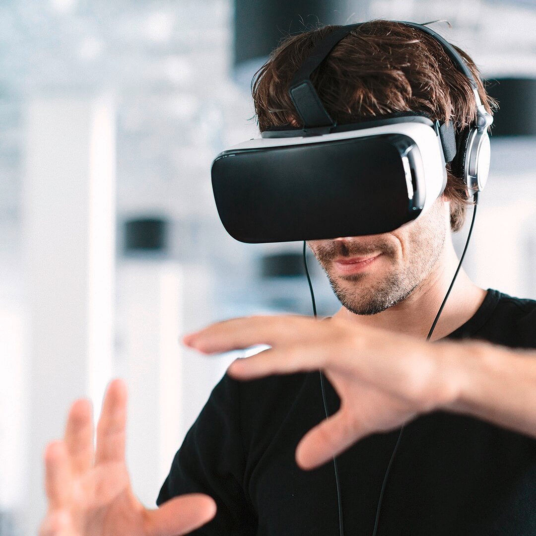 Ein Mann der eine Virtual Reality Brille auf hat und mit den Händen virtuell etwas bewegt. Auf dem Bild steht: 33 Weltmarktführer in echten Zukunftsbranchen. 